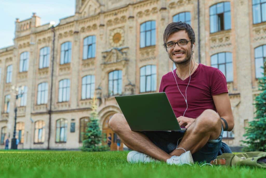 Student mixed race person surfing the web for study on laptop connected to public wifi